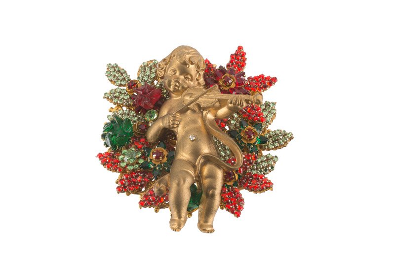 A Stenley Hagler goldtone brooch with a putto playing: A Stenley Hagler goldtone brooch with a putto playing the violin, set with multicolor stones. Signed Stanley Hagler N.Y.C. HxW 9,5 x 8,5 cm.