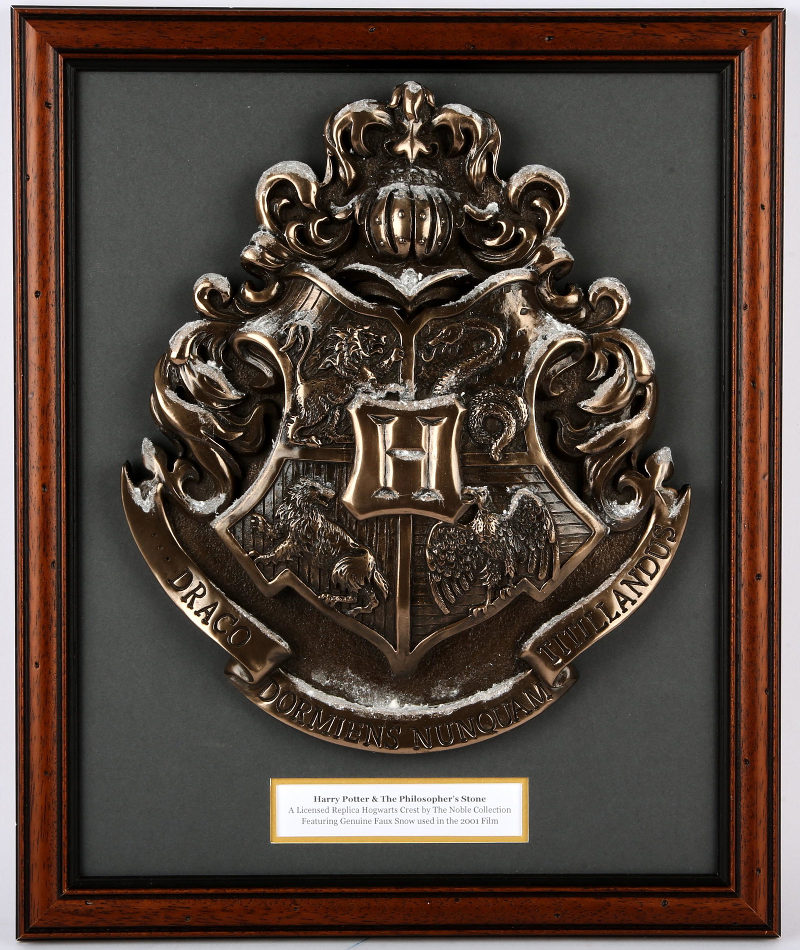 Harry Potter & The Philosopher’s Stone - A License: Harry Potter & The Philosopher’s Stone - A Licensed Replica Hogwarts Crest by The Noble Collection; featuring some of the faux snow used in the Film. Mounted inside a framed display measuring 17