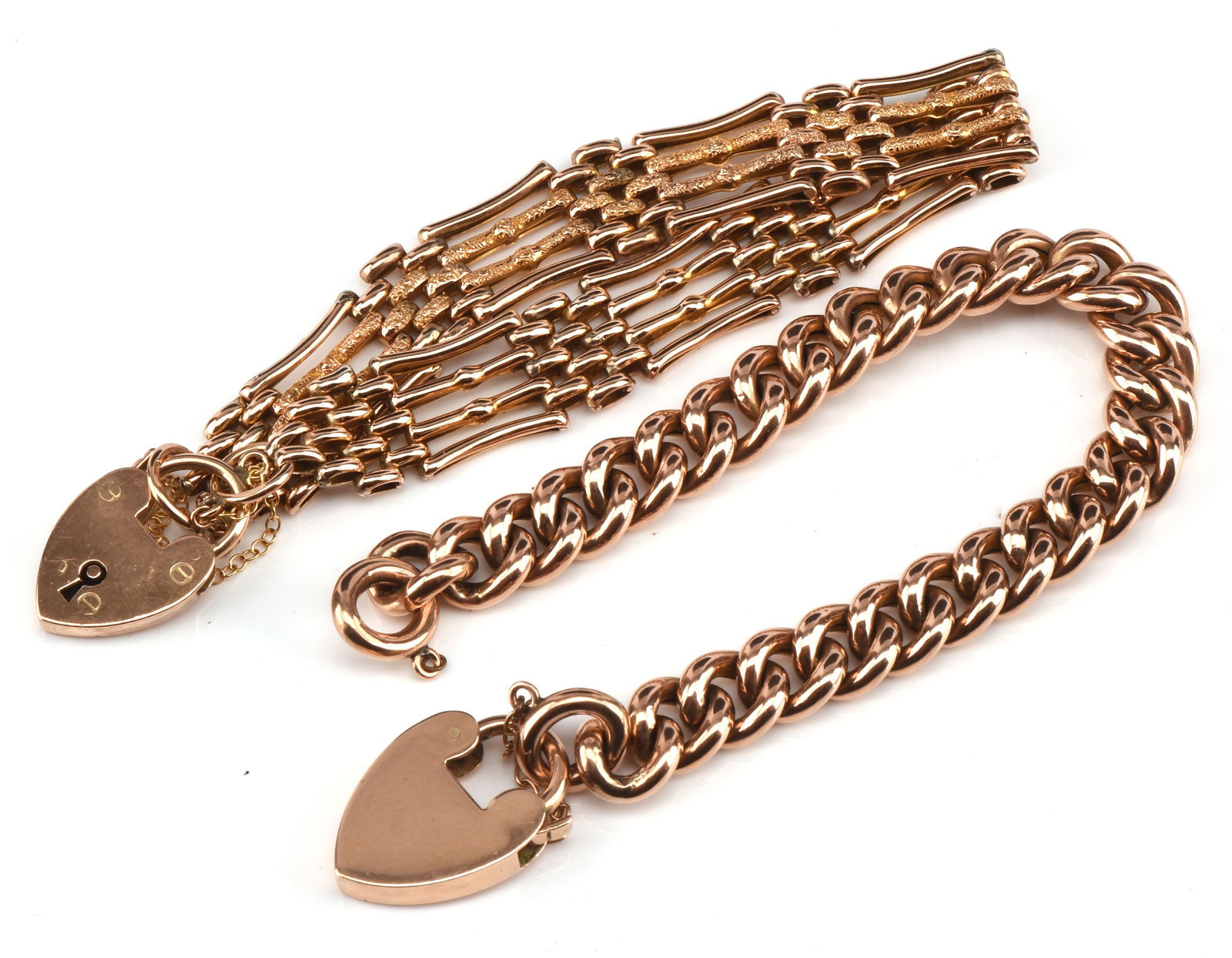 Two charm bracelets, with heart padlock clasps, in: Two charm bracelets, with heart padlock clasps, including an curb chain 20cm long and a fancy link gate bracelet, with 6cm internal diameter, both stamped 9 ct gross weight 41.2 gramsClasps in good wo