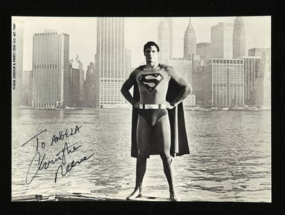 Christopher Reeve (1952-2004) black and white publ: Christopher Reeve (1952-2004) black and white publicity photograph, depicted as Superman standing in front of a New York background, dedicated to Angela and Signed in black ink by the American actor w