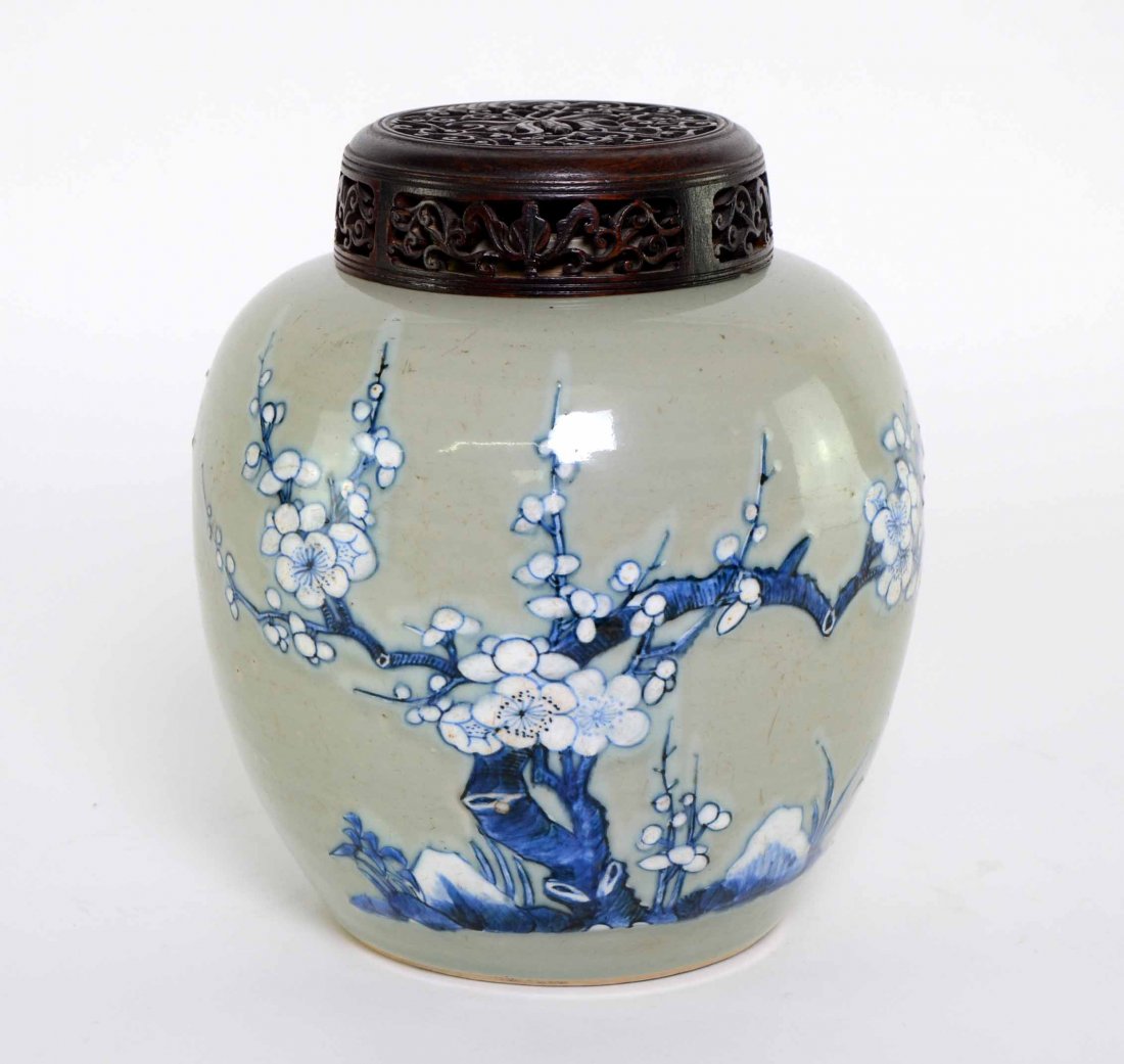 Chinese ginger jar. decorated in blue and white with: Chinese ginger jar. decorated in blue and white with blossoming prunus, rockwork, and birds on a celadon ground. Early 18th Century. with a carved wooden base and a pierced wooden cover. 8¼ x 7½in.