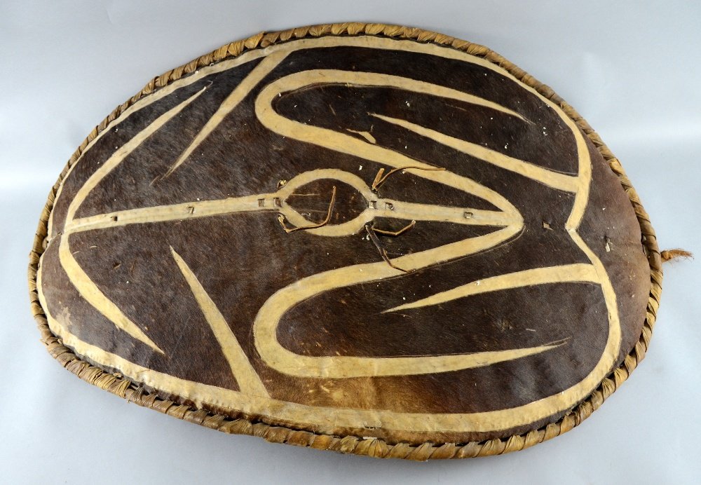 Two African oval hide and decorated shields,: Two African oval hide and decorated shields,
