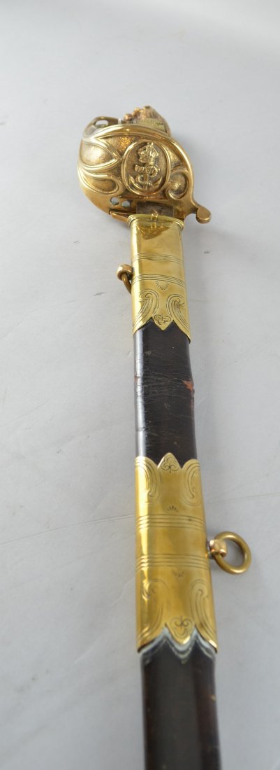 19th century naval officer's sword, with etched: 19th century naval officer's sword, with etched fullered blade, shagreen and wire grip, brass guard and lion's head pommel, in leather and brass mounted scabbard, 37" long.