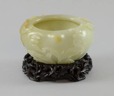 Chinese mutton fat jade brush washer with in-turned: Chinese mutton fat jade brush washer with in-turned rim, carved with five bats above leafy branches, on carved and fitted wooden stand, 3 x 5in. (8 x 13cm)