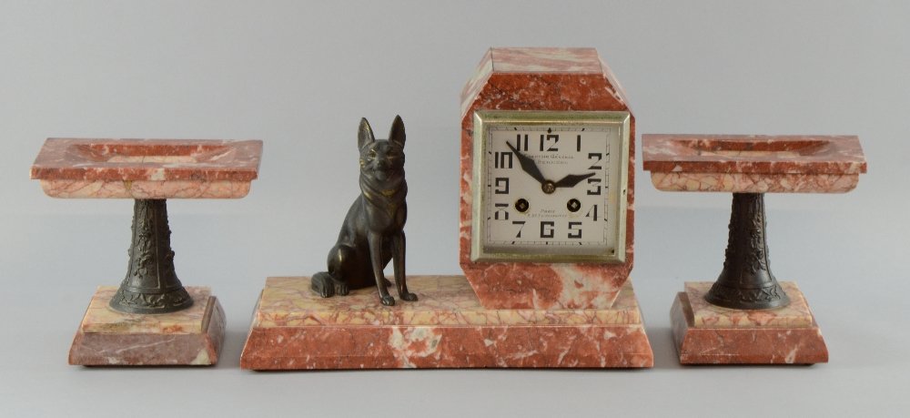 1930's French clock of variegated red marble with: 1930's French clock of variegated red marble with spelter dog and two garniture stands face marked Comptoir General M Schnerb, Bd Poissonniere, Paris, 23cm high, Garniture top has been in two pieces a