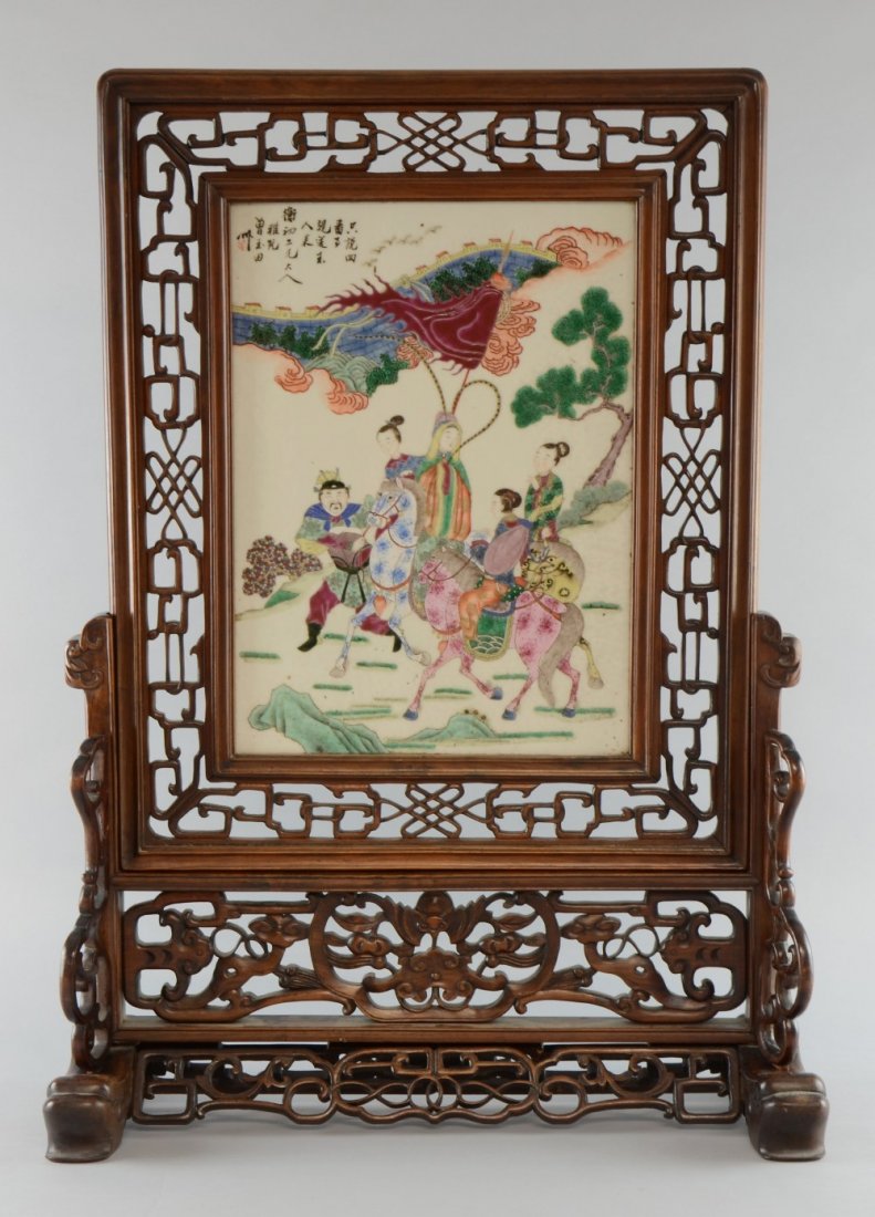 Chinese porcelain table screen enamelled in colours: Chinese porcelain table screen enamelled in colours with figures by the Great Wall of China, with calligraphy and red mark, in a carved and pierced hardwood stand, image size 35.5cm x 26cm,