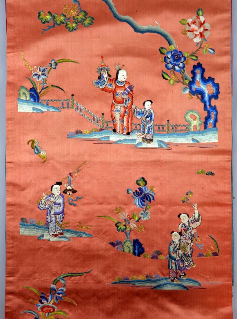Chinese silk hanging, the red ground embroidered with: Chinese silk hanging, the red ground embroidered with figures in a garden, bats, flowers and foliage, the tasseled blue silk surmount embroidered with a figure riding a beast, 223cm x 44cm,