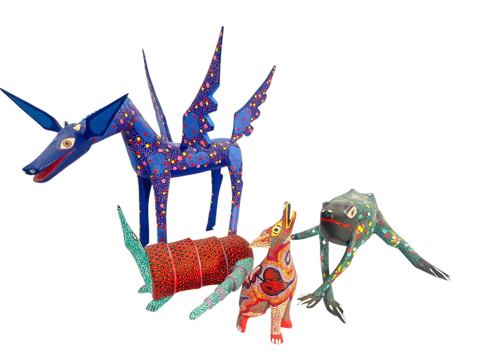 A Collection of Oaxacan Alebrije Carved Wood Animals: Includes a coyote, an armadillo, a winged horse, and a frog. All pieces are signed by their individual artists on the bottom- please see photos. The winged horse is the largest and measures 13" H x 17