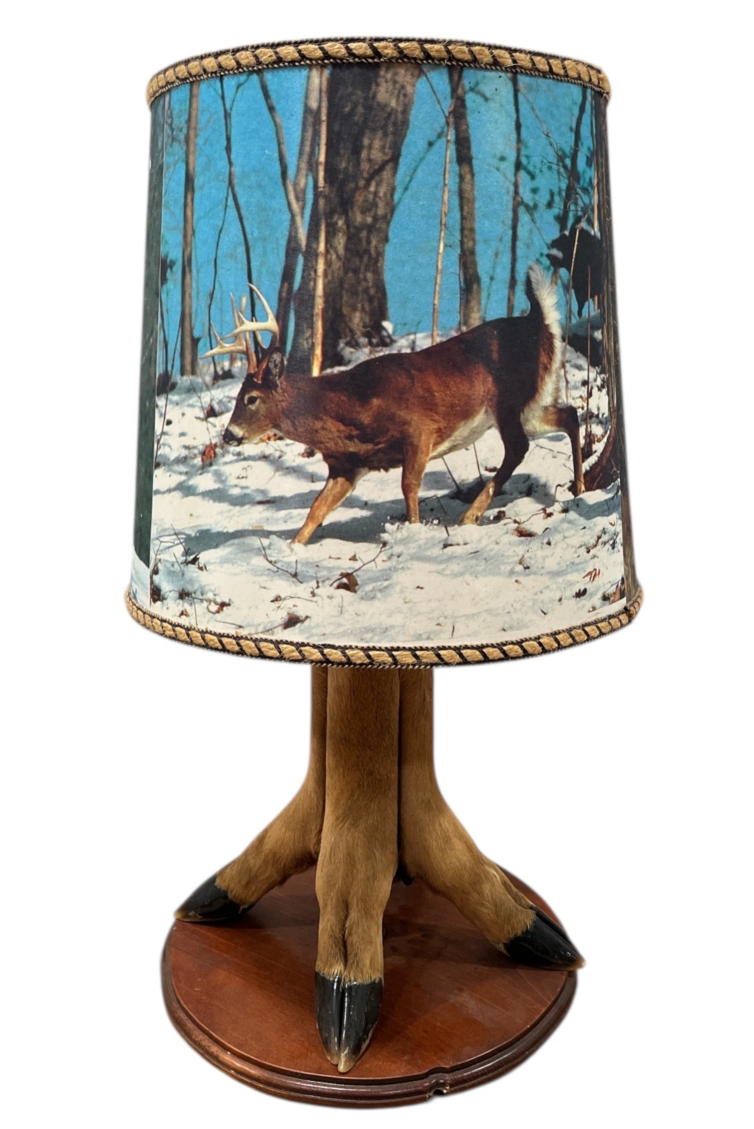 Vintage Deer Hoof Taxidermy Lamp: 21" H x 11" DIA at base x 12" DIA on shade. Shade depicts a winter and summer scene with deer.
