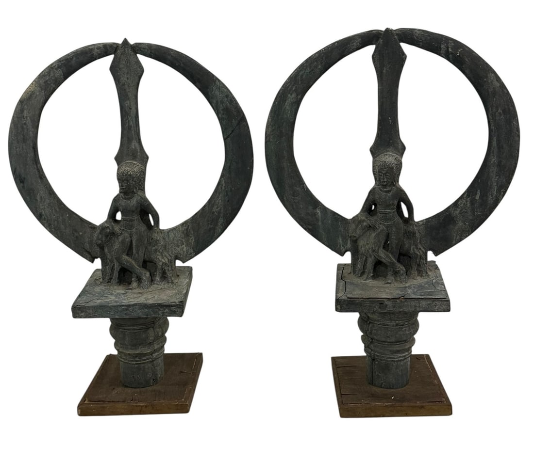 A Pair of Trisula Statues: 24" H x 16" W x 7.25" D. "A trident (trisula) in two parts (prongs and separate round base joined to the upper part by a modern wooden shaft), with an image of Siva Vrsavahana, the god leaning up agai