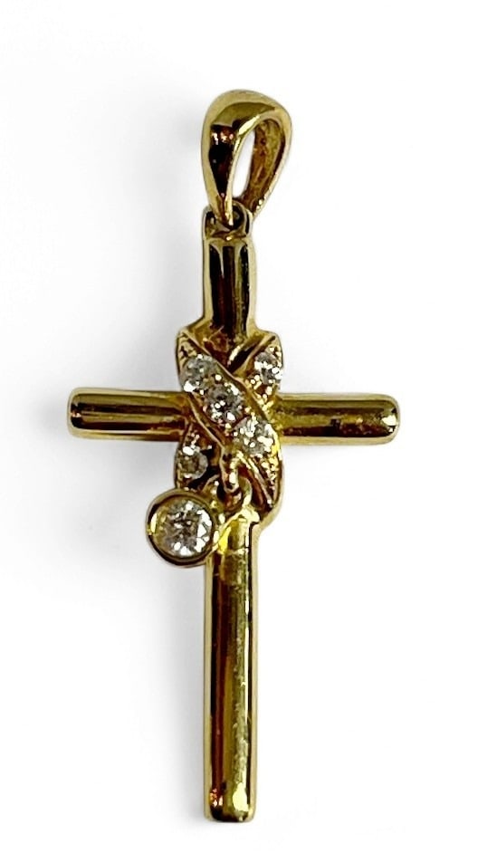 An 18k Gold and Diamond Cross Pendant: Measures 1" H x .5" W, includes five diamond chips wrapped around cross and one slightly larger diamond dangling from cross. Piece weighs 1.21dwt including stones.