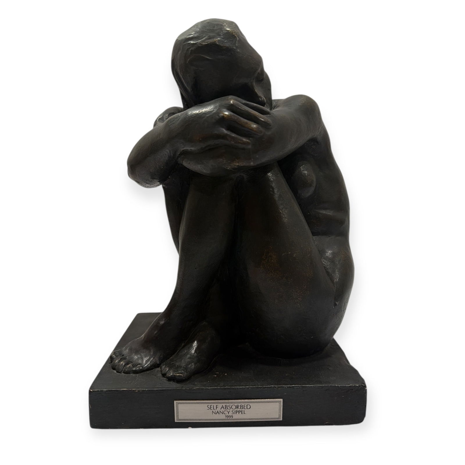A Sculpture of Woman, NANCY SIPPLE: In the style of Aristide Maillol. Shows a woman sitting, curled in a ball. Composite material on body and base. Measures 11" H x 7.5" W x 6" D. Includes a plaque and signature from artist Nancy Sipple