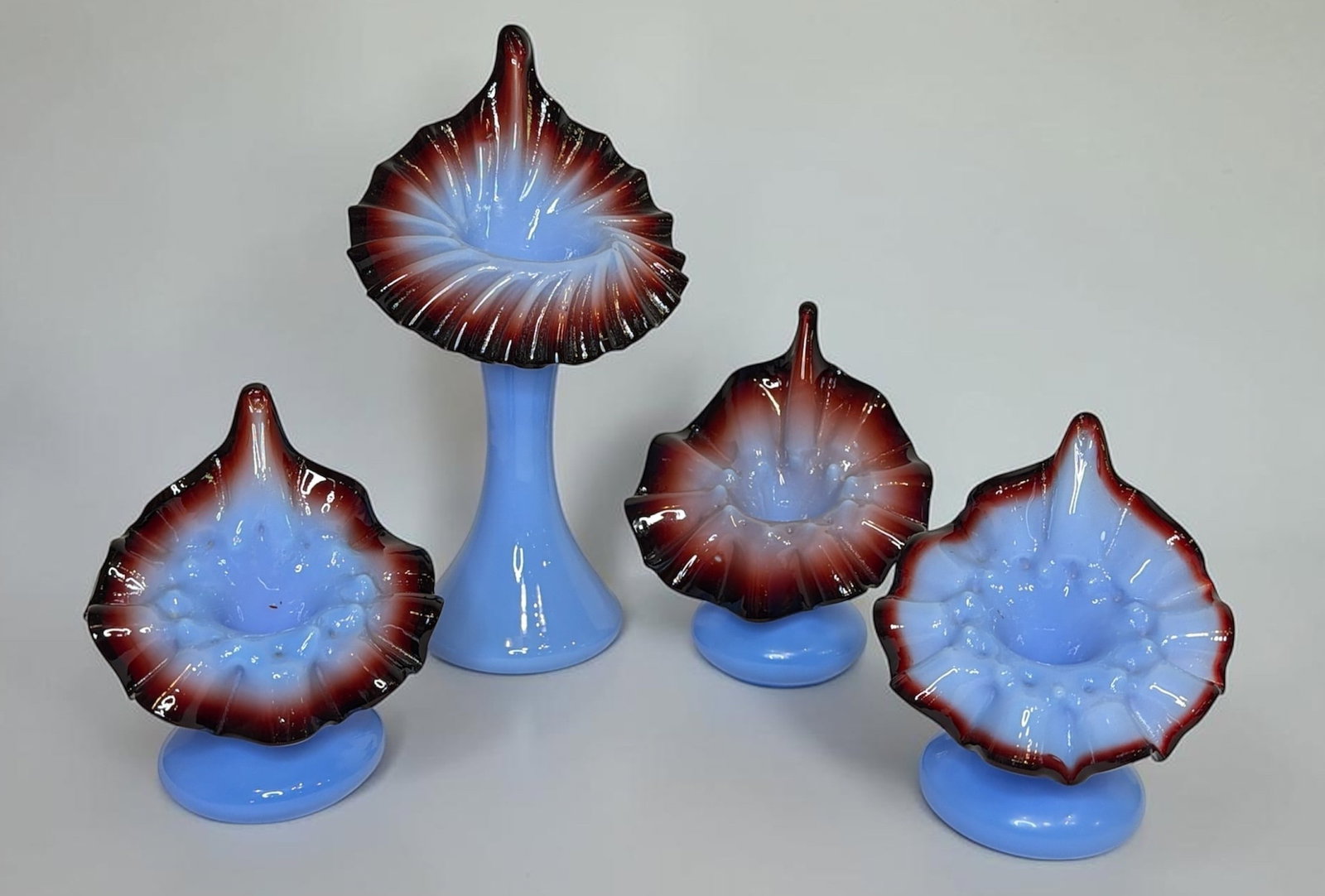 Four Oxblood and Blue Art Glass Jack In The Pulpit Vases: Features four victorian oxblood and blue hobnail jack-in-the-pulpit vases. Largest measures 10" H x 5.25" W x 4" D. Three smaller vases all measure approx. 5.5" H x 4.75" W x 4" D.