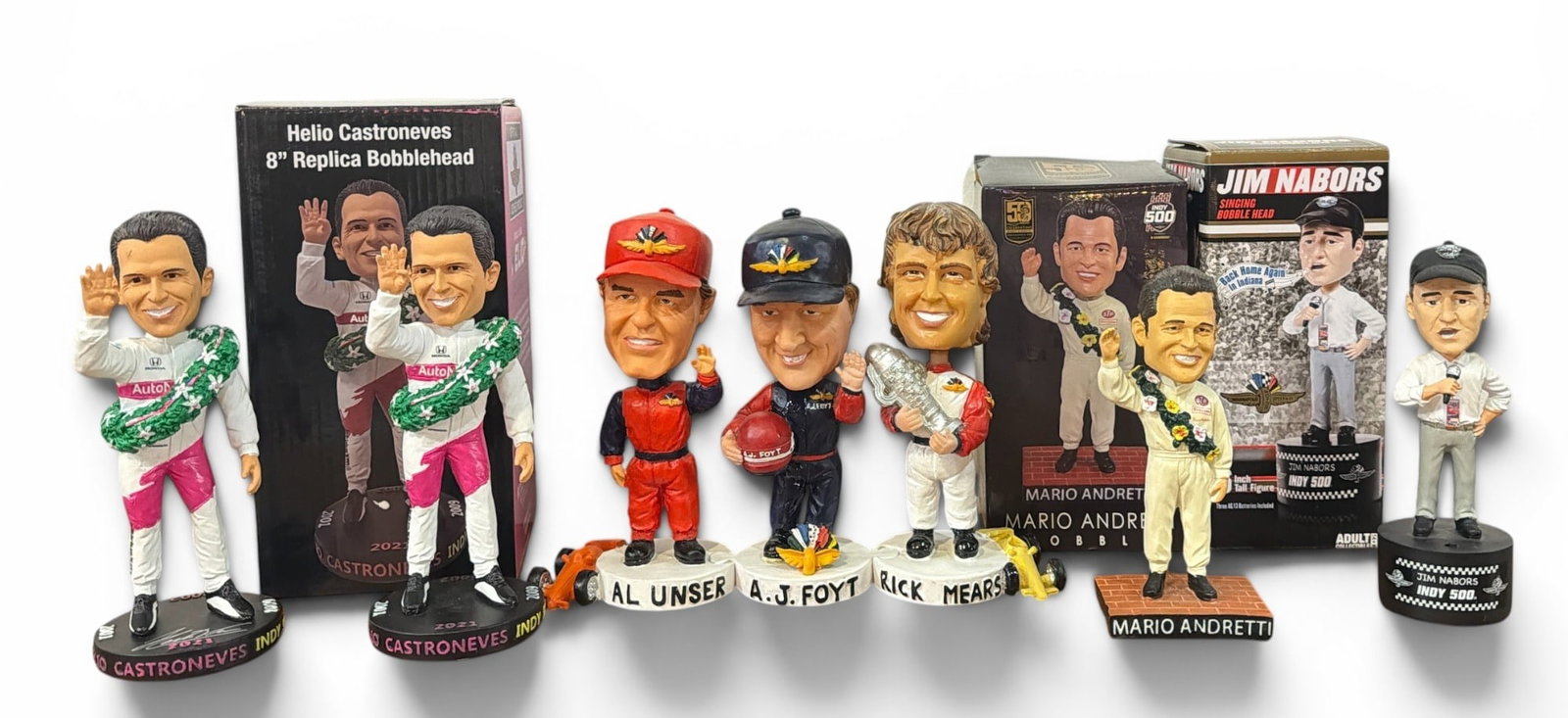 Collection of Indianapolis 500 Car Racing Bobble Heads: Includes bobbleheads of Mario Andretti, a singing bobblehead of Jim Nabors, two bobbleheads of Helio Castroneves, and a connecting bobblehead of Rick Mears, A. J. Foyt, Al Unser.