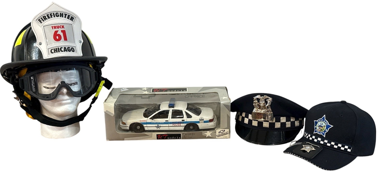 Collection Chicago Police and Firefighter Uniform Helmets, Hats: Includes a 1:18 scale diecast UT Models Chicago police squad car, Cairns MSA safety firefighter helmet, Cairns 10029699 SEI 2013 Edition goggles, an obsolete Chicago Police Department hat and badge,