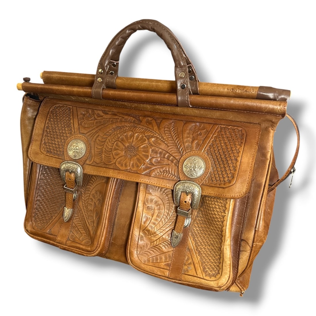 Southwestern Tooled Leather Work Bag: Intricately tooled leather with silver tones buckles and accents. Short and long staps for easy carrying in addition to expanding storage on the sides. Bag itself measures approx. 15" H x 20" W x 10" 