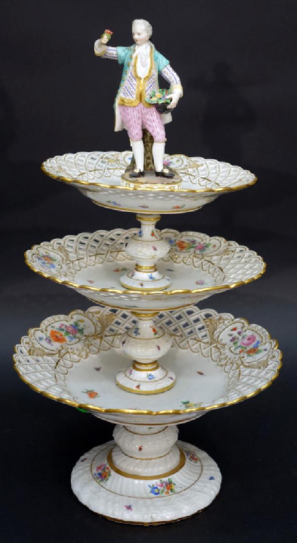 MEISSEN TIERED COMPOTE: Painted porcelain, crossed swords mark, figural finial over three tiered reticulated plates, painted with flowers and insects; right hand has repair; H-19", G-VG