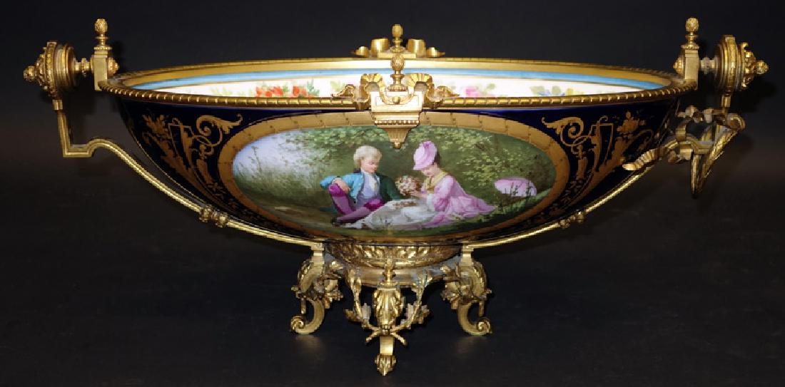 PAINTED PORCELAIN & BRONZE ORMOLU CENTER BOWL/COMPOTE: Courting scene with floral vignette on reverse; gilt enamel highlights; missing ormolu wreath and banner off one end; H-10", L-22", VG