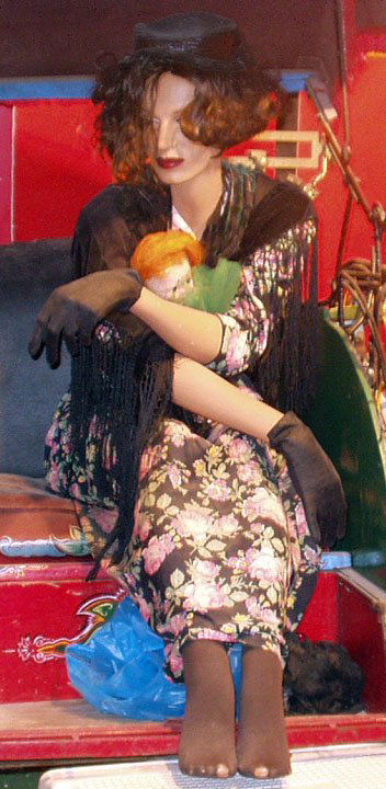 SEATED FEMALE MANNEQUIN FAIR GO-ER: Dressed as fair-goer; holding kewpie doll; no shoes; kewpie missing arm; VG.