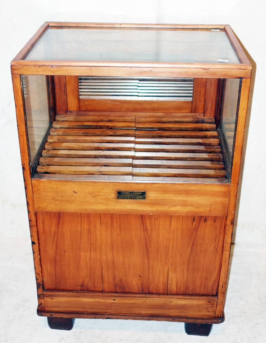 COUNTRY STORE DISPLAY CASE: Garfinkle & Steinberg label; mixed wood; drop down back; rear storage compartment; old refinish; normal wear; H-35", W-22", G-VG