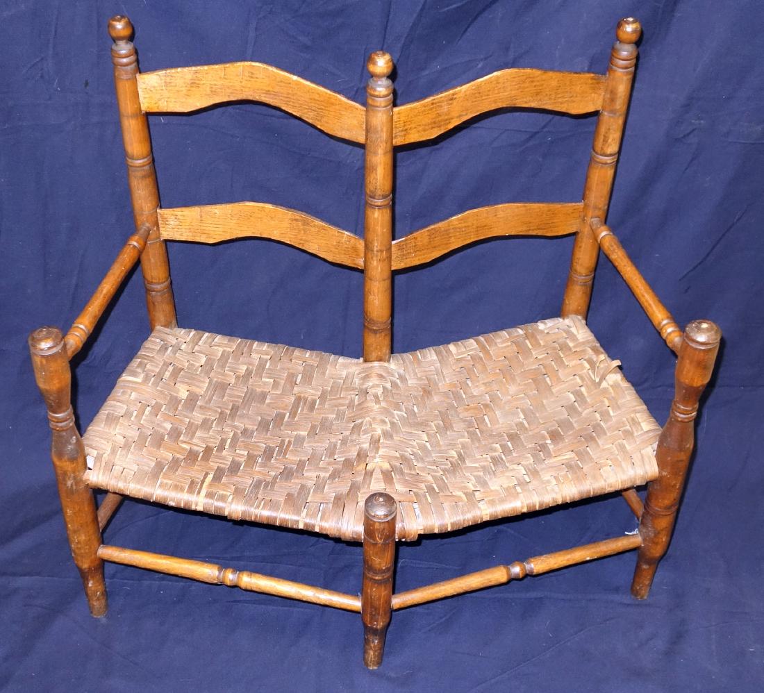 UNUSUAL CHILD'S DOUBLE SETTEE: Two ladder back, splint seat double chair back; comes to a point in the front and angles back; seat has some damage; normal wear; H-25", W-27", G-VG