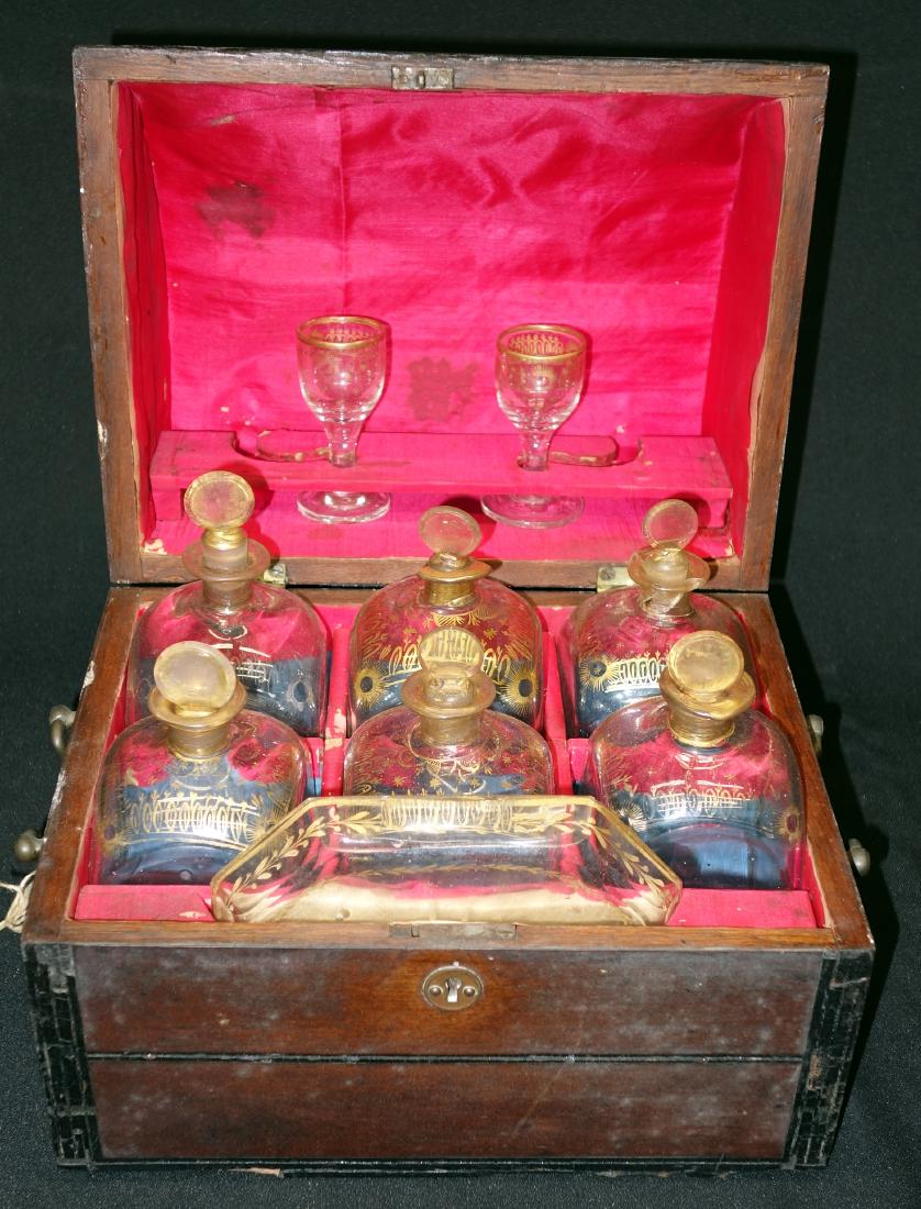EARLY CELLERETTE: Mahogany case; (6) gilt decorated decanters, (1) small glass tray and (2) cordials; accompanied with letter of provenance and story from Capt. John Jillard; wear, chips, case needs work; H-10", W-11",
