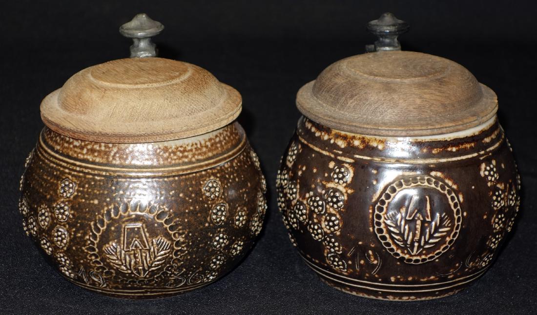 BROWN STONEWARE STEINS (2): Oak lids; relief decoration; (1/2L); H- 5"; V-G