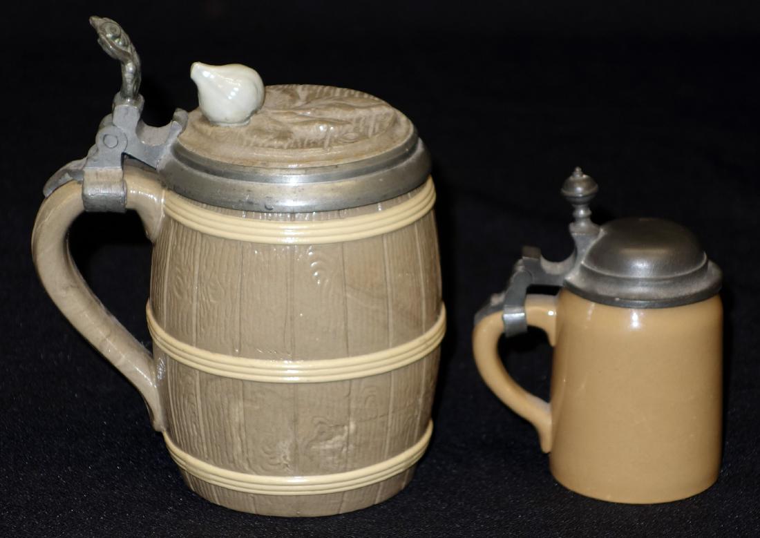METTLACH STEINS (2): (1) miniature stein; pewter lid; #2303; (1) barrel form; inlaid lid; #675: small chip on bottom; interior discoloration; H- 3 1/2- 5"; VG-F