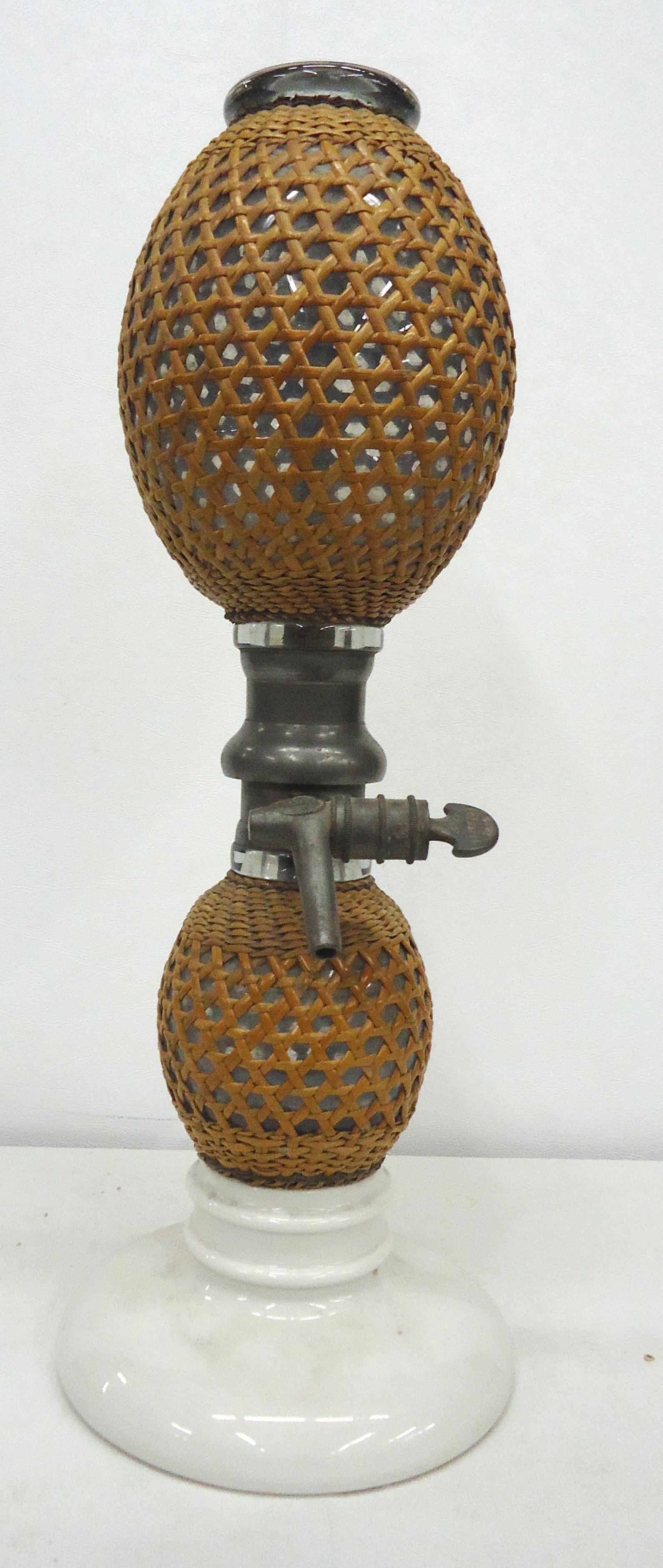 FRENCH SELTZER BOTTLE: Vintage; figure-8 clear glass covered wicker with porcelain base and metal spigot; H-18"; VG-EX