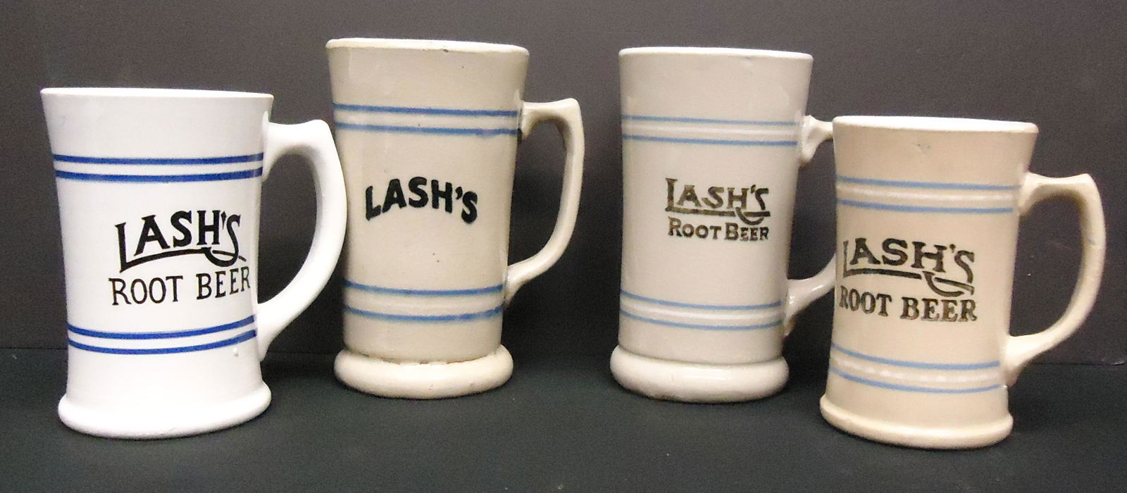 LASH'S ROOT BEER MUGS (4): Ceramic; all different; some crazing; H-5 1/2"- 6 1/2"; G-VG