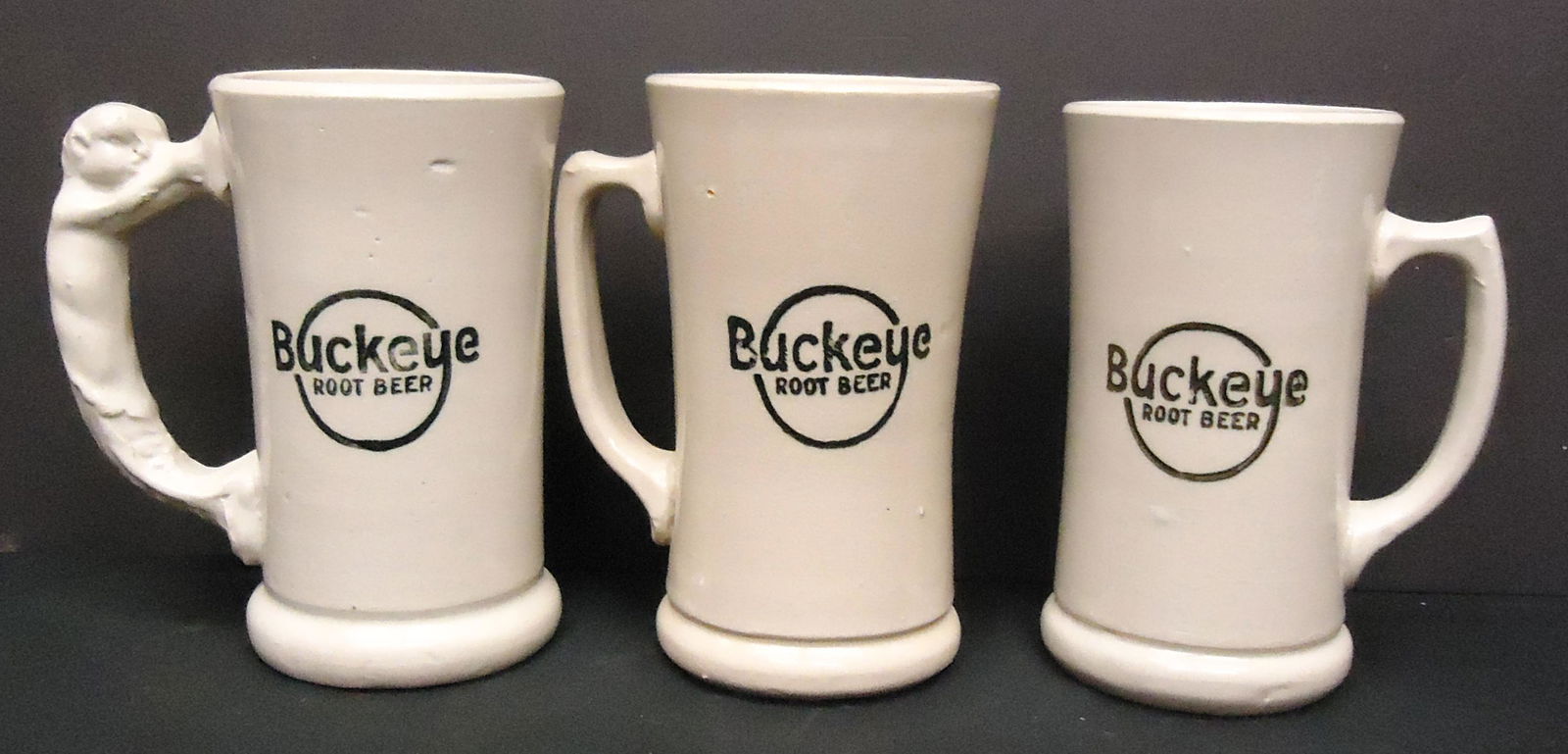 BUCKEYE ROOT BEER MUGS (3): Ceramic; (1) figural handle; (1) left hand (?); (1) right hand (?); H-6 1/4"; G-VG