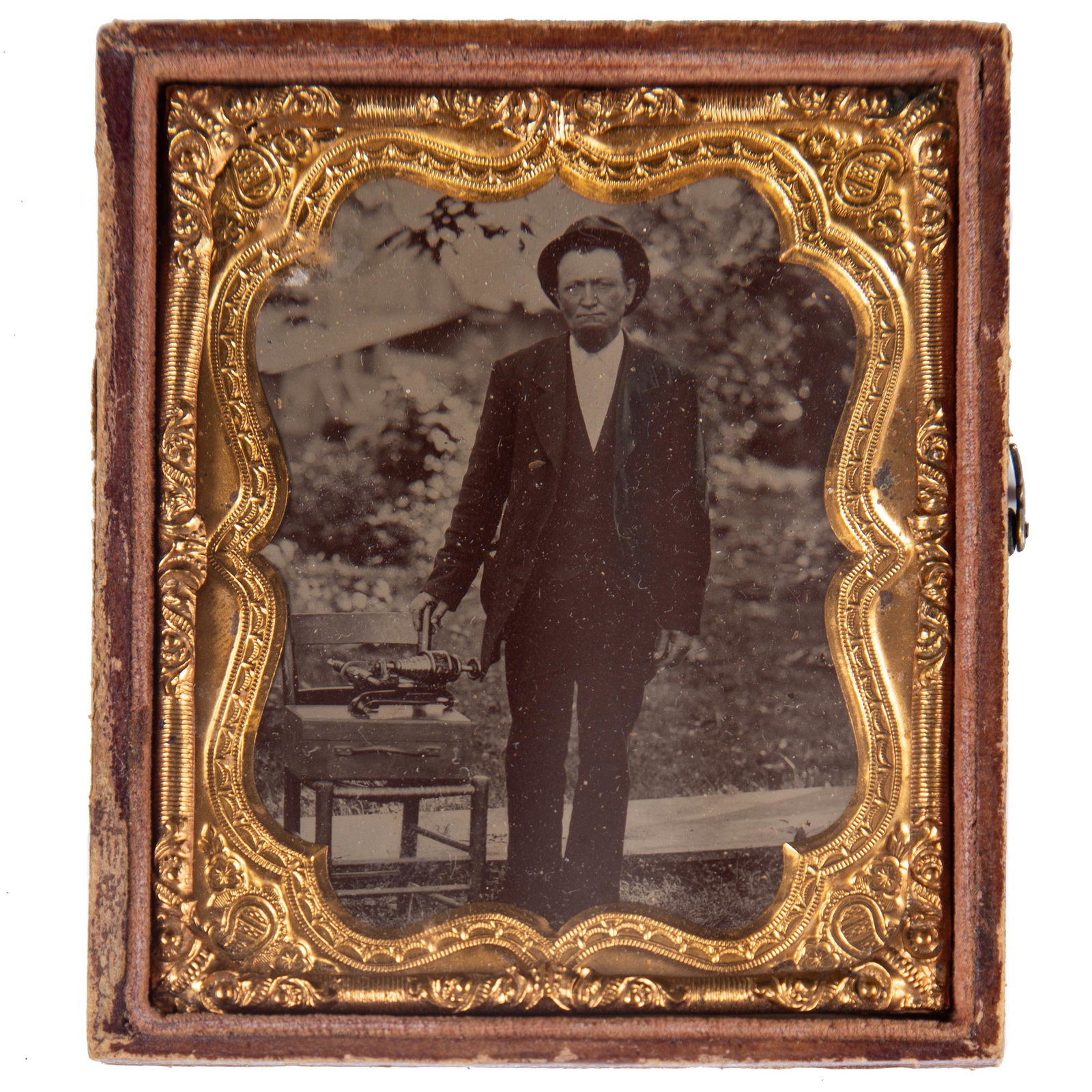 OCCUPATIONAL TINTYPE OF SALESMAN: Ninth plate; bright image of salesman standing beside unusual machine; possibly an image of a patient standing next to a quackery device; ornate gilt mat; plane case, missing half; G-VG