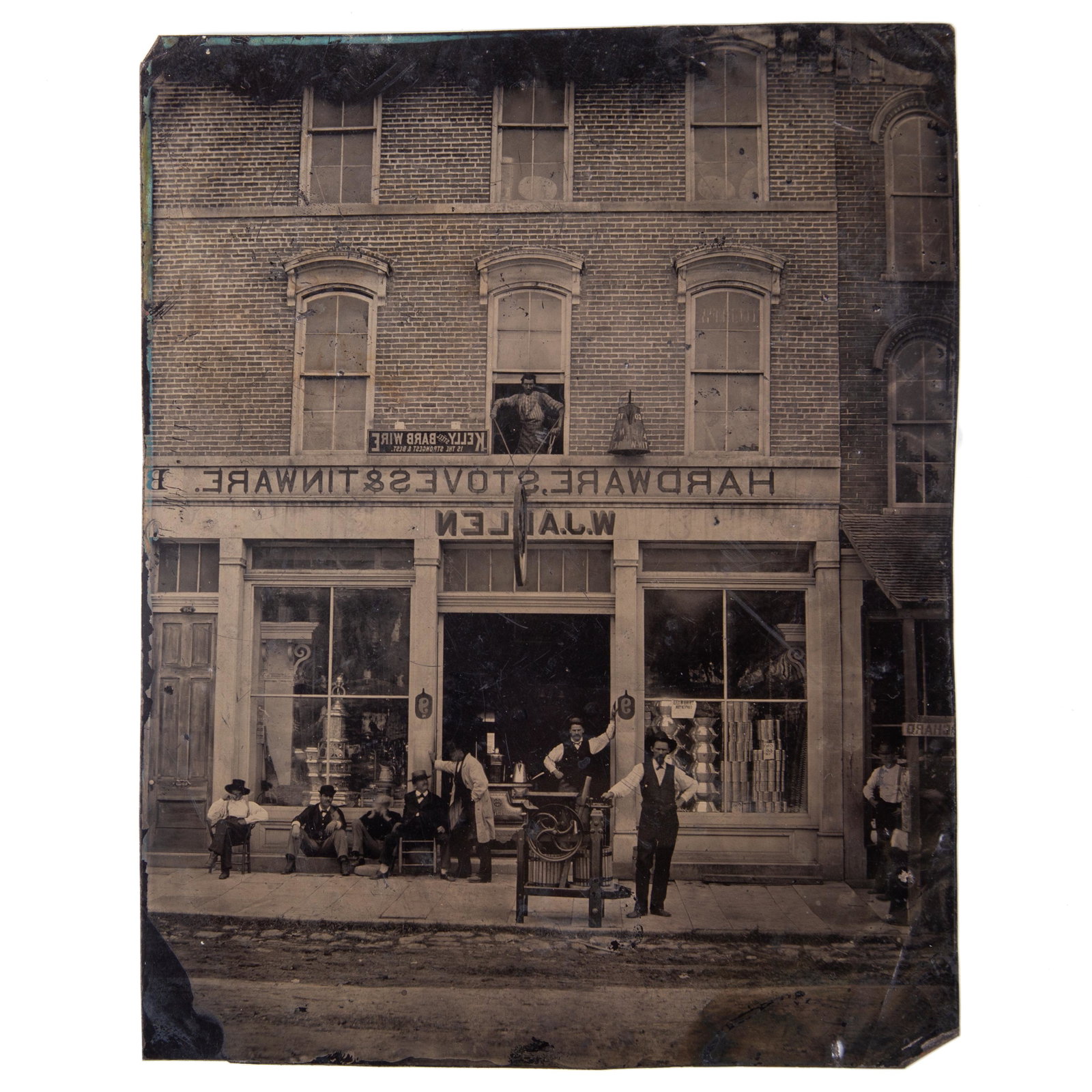 TINTYPE HARDWARE STORE: Full plate; image of "W. J. Allen Hardware, Stoves, Tinware" brick store with gentleman in front with corn sheller and merchandise in windows; includes gentleman in upstairs window and large tin coffe