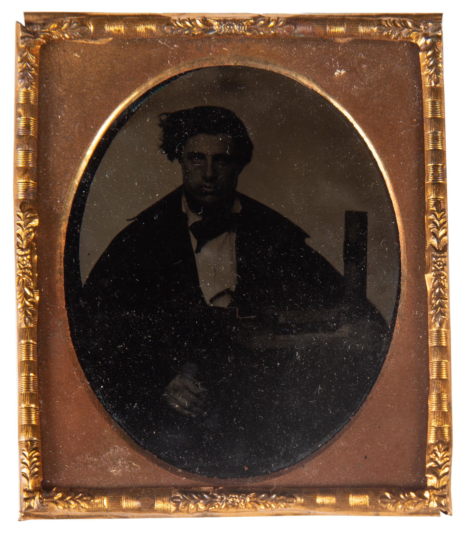 OCCUPATIONAL TINTYPE: 6th plate; image of young man, inventor (?) or possibly salesman with apparatus; gilt metal mat; no case; image dark; G