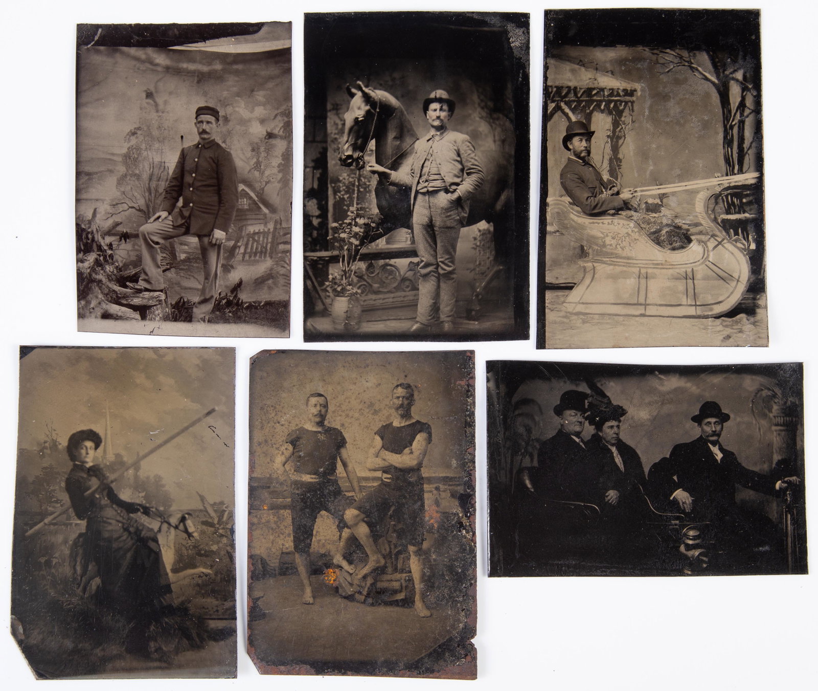 STUDIO TINTYPES (6): 6th plates; (1) man with horse statue; (1) man in sleigh; (1) woman jouster; (1) group in a car; (1) men in swimsuits; somewhat dark; G-VG