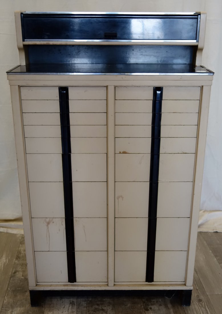 AMERICAN CABINET CO. DECO DENTAL CABINET: Enameled wood and masonite; hinged door shelf over (18) drawers; original metal labels; (1) piece of molding needs gluing; scratches and scuffs; H-52", W-31", Depth-12", G-VG