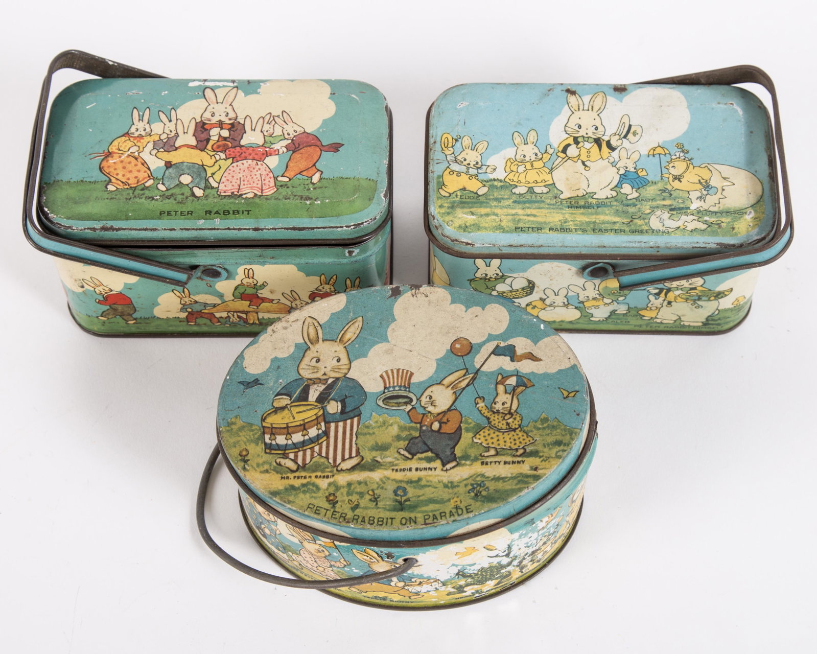 EASTER TINDECO CANDY BOXES (3): Tin litho; (1) Peter Rabbit's Easter Greeting; (1) Peter Rabbit on Parade; (1) Peter Rabbit; all stamped "Tindeco" on bottom; minor paint loss overall; some dents, scratches and fading; L-4 3/4", G-VG