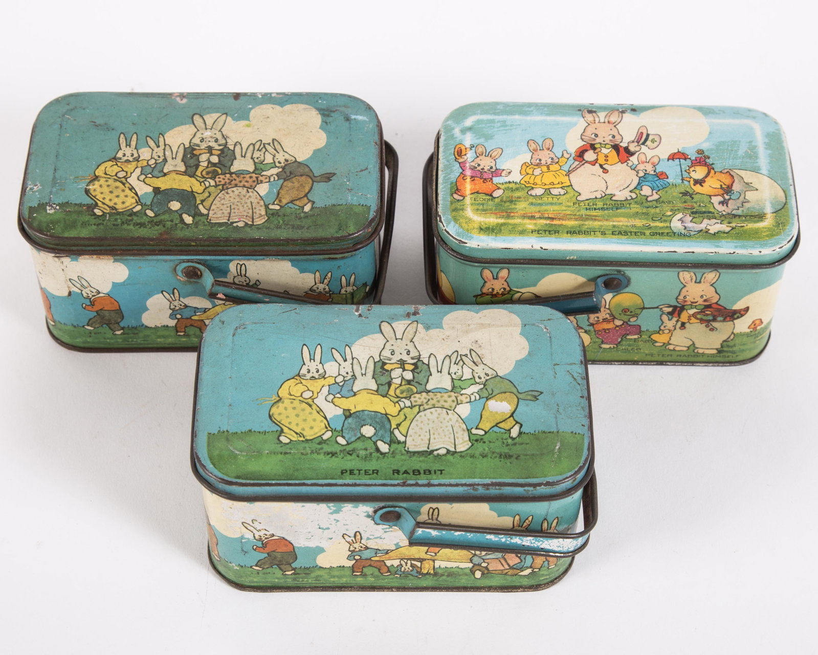 EASTER TINDECO CANDY BOXES (3): Tin litho; (1) Peter Rabbit's Easter Greeting; (2) Peter Rabbit; all stamped "Tindeco" on bottom; minor paint loss overall; some dents, scratches and fading; L-4 3/4", G-VG