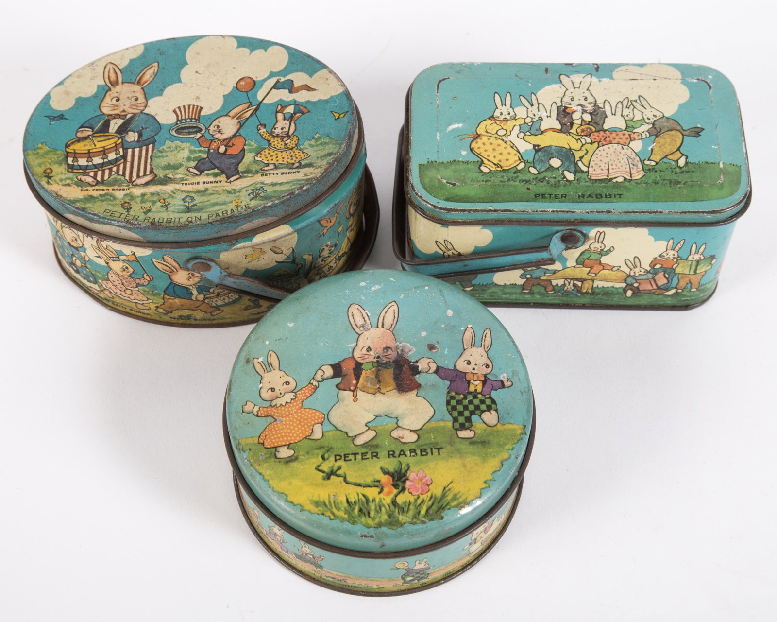 EASTER TINDECO CANDY BOXES (3): Tin litho; (2) Peter Rabbit; (1) Peter Rabbit on Parade; all stamped "Tindeco" on bottom; minor paint loss overall; some dents, scratches and fading; L-4 3/4", G-VG