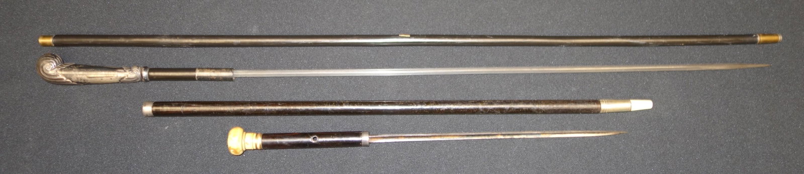 SWORD SWAGGER STICKS AND CANES (2): All containing blades. (1) Silver handle-English-Diamond Blade. (1) Bone Knob swagger stick-engraved John Wattell (?) Grove blade. Wear. L24-36 G-VG