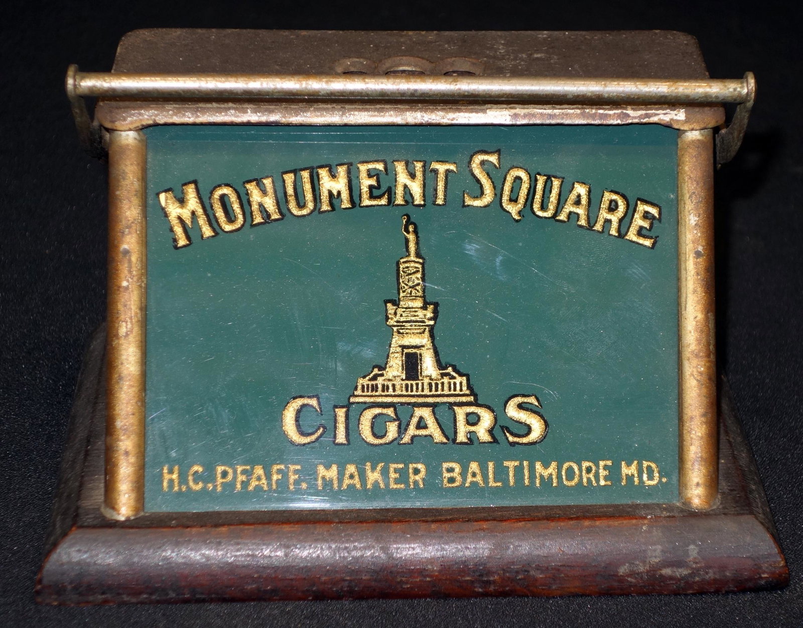 MONUMENT SQUARE CIGAR CUTTER-BALTIMORE: Counter top lever activated. Reverse painted glass. Metal. Wood base. Wear. L 8" F- G