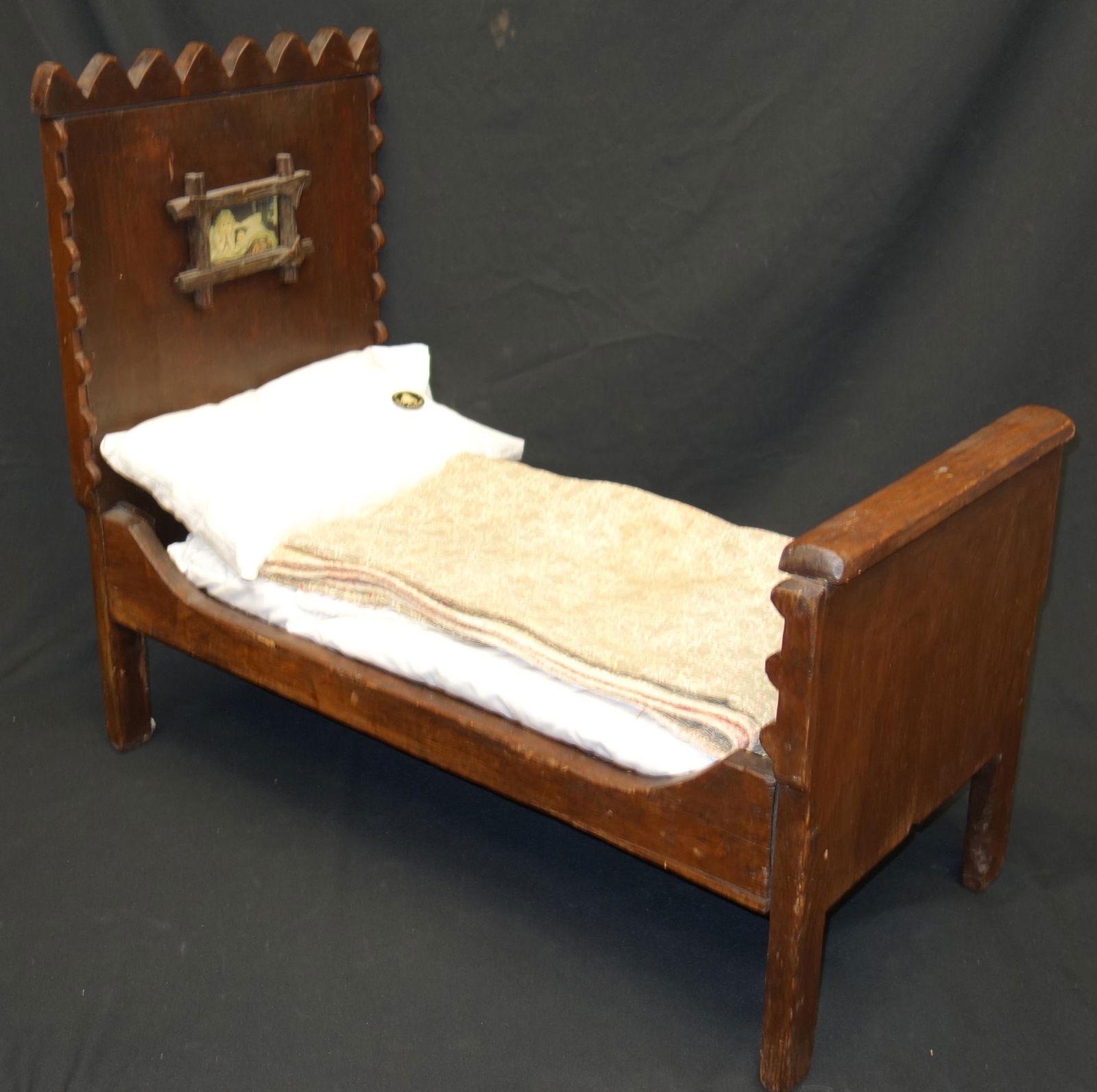 ANTIQUE DOLL BED: Together with (2) quilts, (2) pillows; wooden; appears to be hand makde; baby charming pin and framed imagery on headboard; headboard is loose, shows stress cracks; chip in base of footboard; quilts s