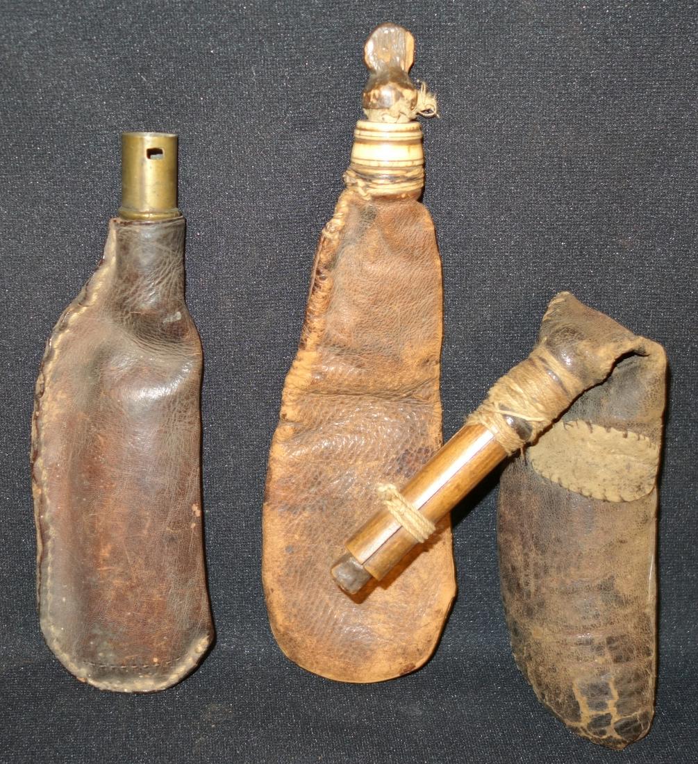 ANTIQUE POWDER FLASKS (2): leather, hand stitched; (1) bone and wood top; (1) wood top; (1) brass top with piece missing; leather rough and dry; longest L-10", F-G