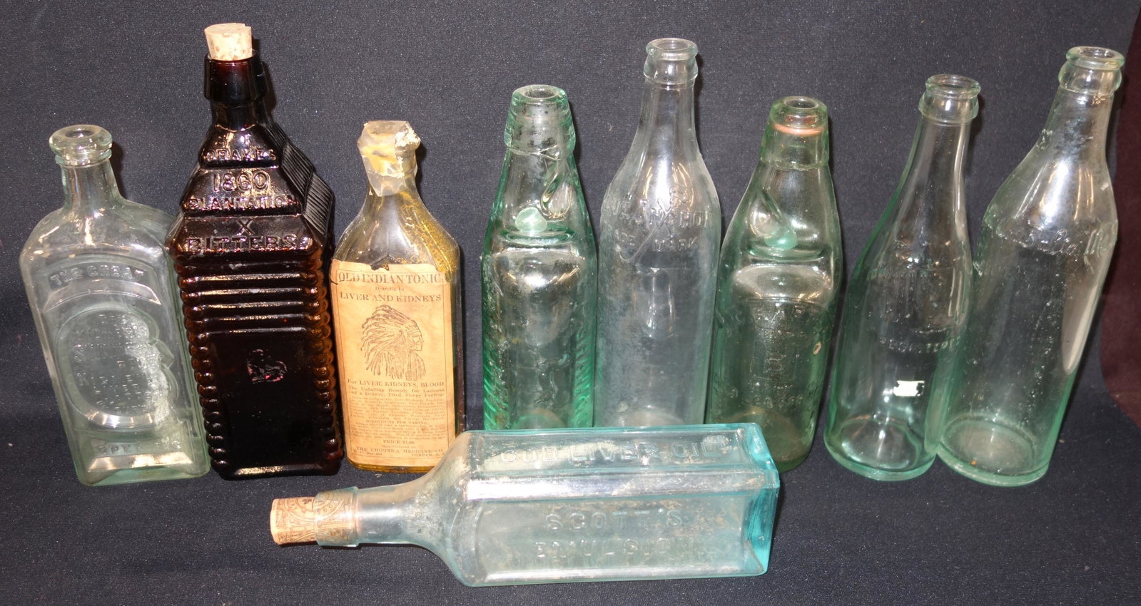 EARLY BOTTLES (9): Glass; (1) with original paper label "Old Indian Tonic"; (1) JJ Wolf's Brewery - Phila; (2) bottles with marble, 1-E.P. Shaw & Co. Wakefield & Leeds, 1-J. C. Hartley Cold Lea Springs Kingsley Staffs; 