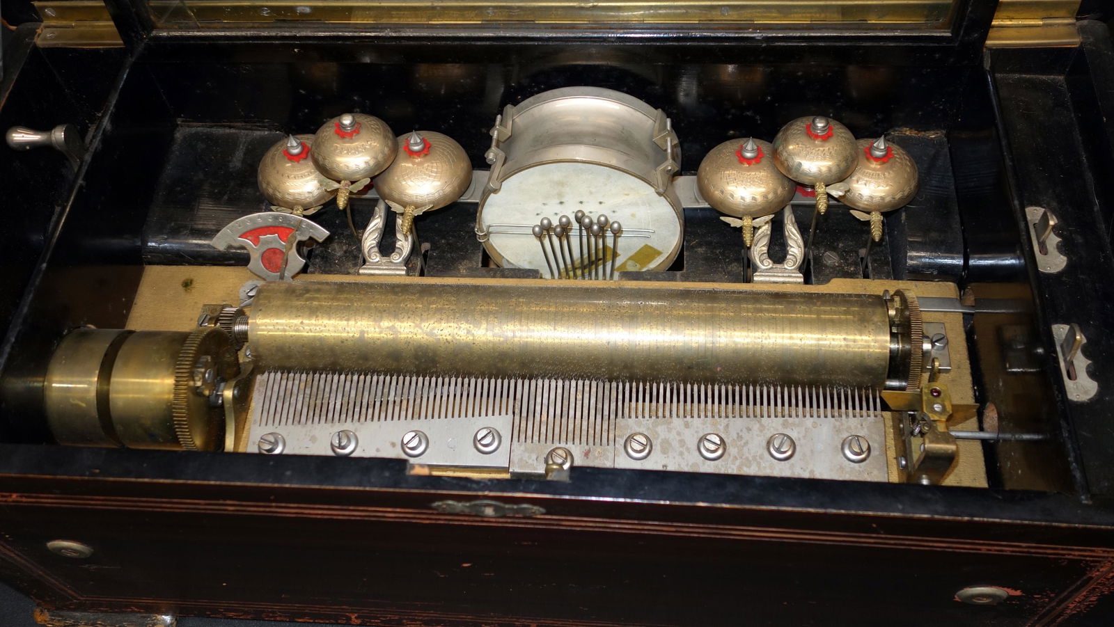 CYLINDER MUSIC BOX: Drum, bees & Bells (6)-13" cylinder-Trommel & Glocken (8) airs label. Faux wood painted case with inlaid top. Music box needs cleaning & tuning. Crank sticking-out of tune-glass cover cracked. Wear to