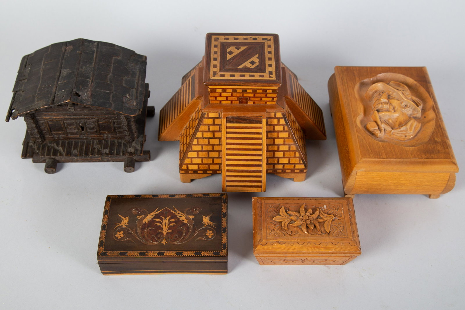 FIGURAL WOOD BOXES (5): Carved & inlaid wood. (1) Pyramid-pop up cigarette box with match holder (1) Cottage-black forest-lift lid-has locking mechanism but no key. Some shingle loss. (1) Tyrolean cigarette box with carved f