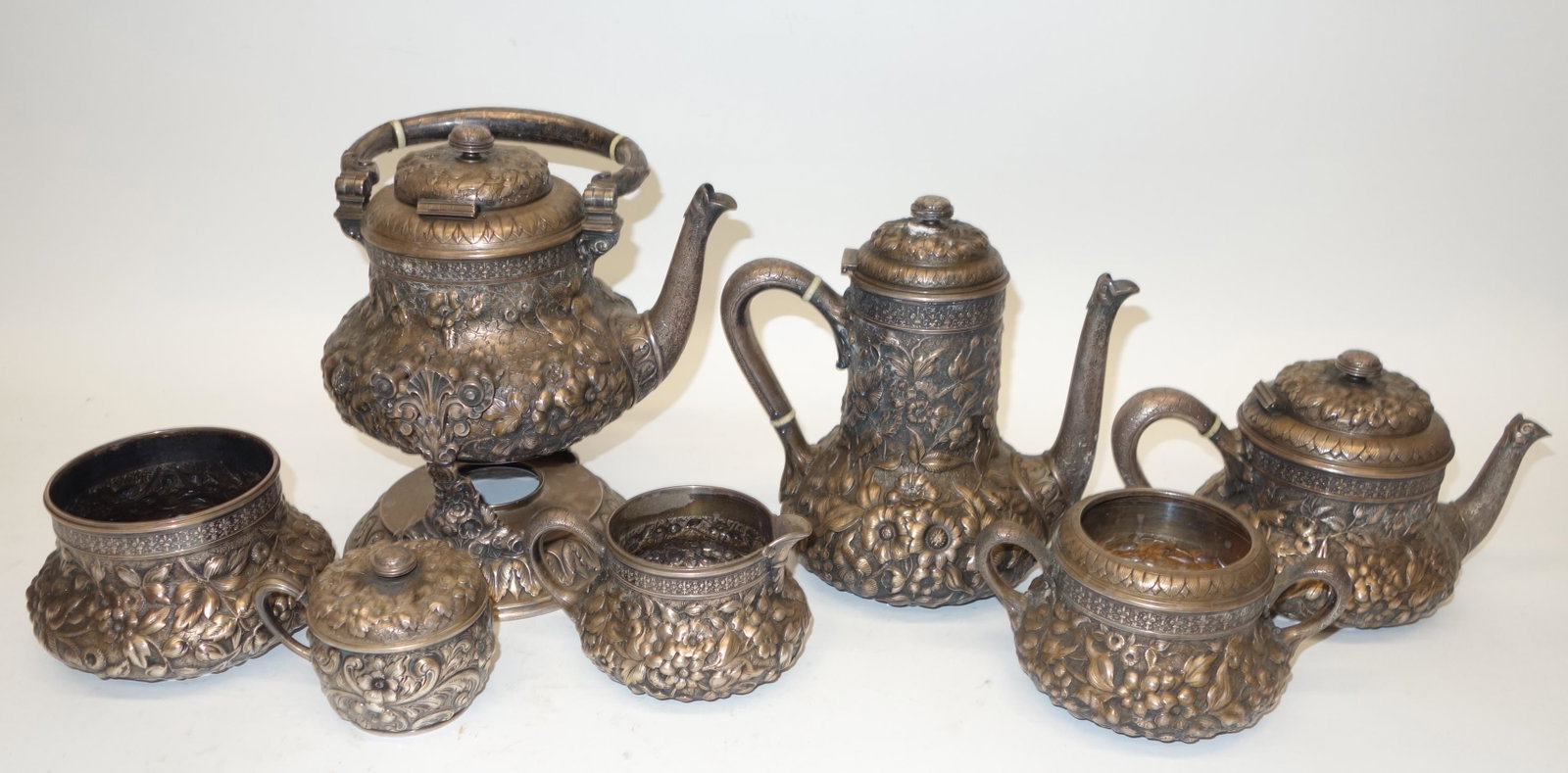 WILLIAM WILSON STERLING COFFEE/TEA SERVICE (7) PCS.: Victorian respousse and engraved service; illegible monogram on bottoms; (1) coffee pot on stand, swing handle, H-11", 53.2 TO; (1) coffee pot, H-8 1/2", 28.7 TO; (1) teapot, H-6", 23.1 TO; (1) wasteb
