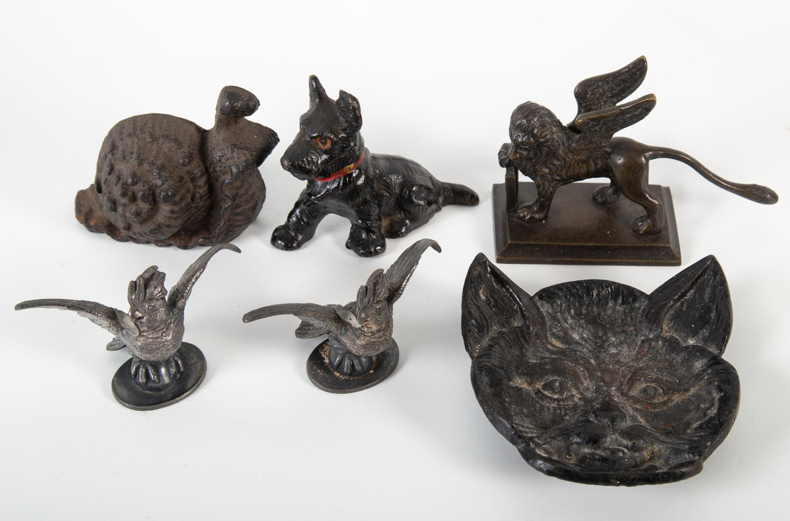 COLLECTIBLE ANIMAL OBJECTS (6): (1) cat face dish; (1) snail door stop; (1) Scottie paperweight; (1) winged lion paperweight; (2) plated parrots; marked 1885; normal wear; H- 2"-4"; G-VG