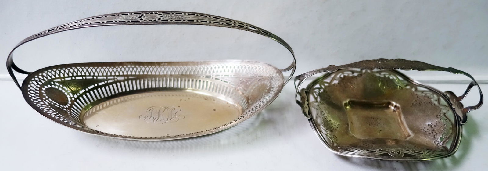STERLING BASKETS (2): Both monogrammed "J.K.M."; (1) Bread basket- Gorham (A9693/2), reticulated plain basket, L-12", [8.59 T.O.]; (1) Candy basket # 540, reticulated plain basket w/ eight scroll engravings, L- 8", [5.74 T