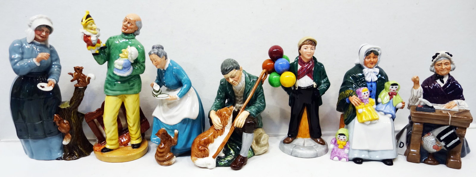 ROYAL DOULTON FIGURINES (7): The Rag Doll Seller HN2944- 1983 signed; Schoolmarm HN2223- 1957; The Master HN2325- 1956; Balloon Boy HN2934- 1983; Good Friends HN2783- 1984; The Favourite HN2249- 1959; Punch and Judy Man HN2765- 1